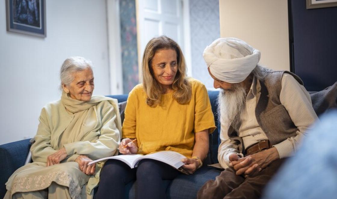 Elderly Asian couple talking with woman in yellow