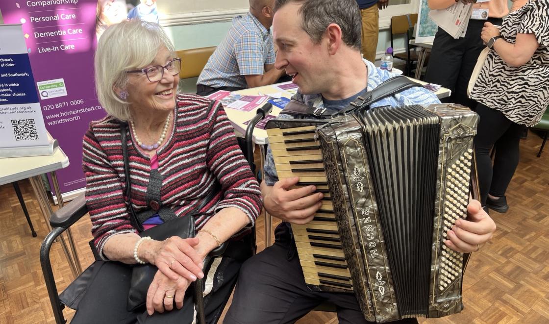 Pauline Jones and Alistair Sutherland are smiling. Alistair is holding a piano accordion 