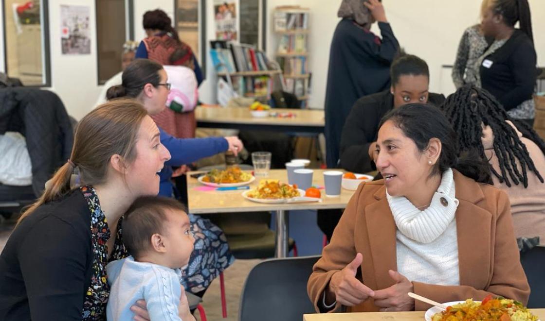 Two people talking over lunch with baby 