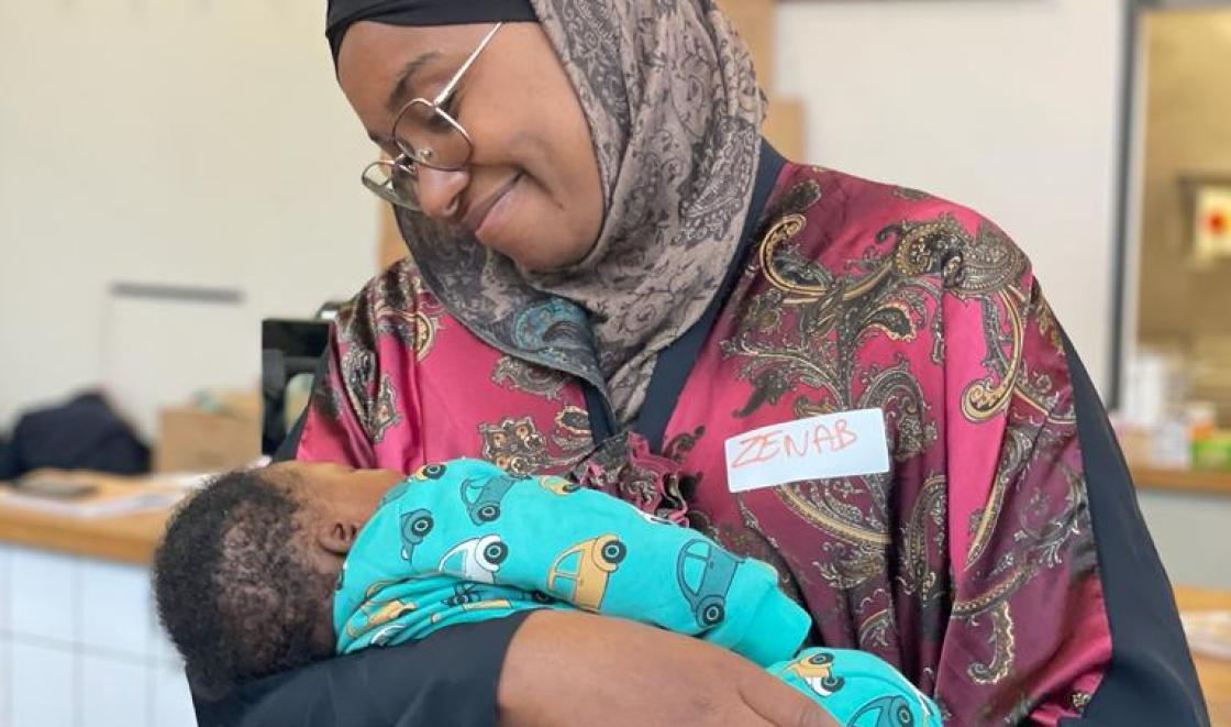 Zenab holding a baby at the maternity listening event 