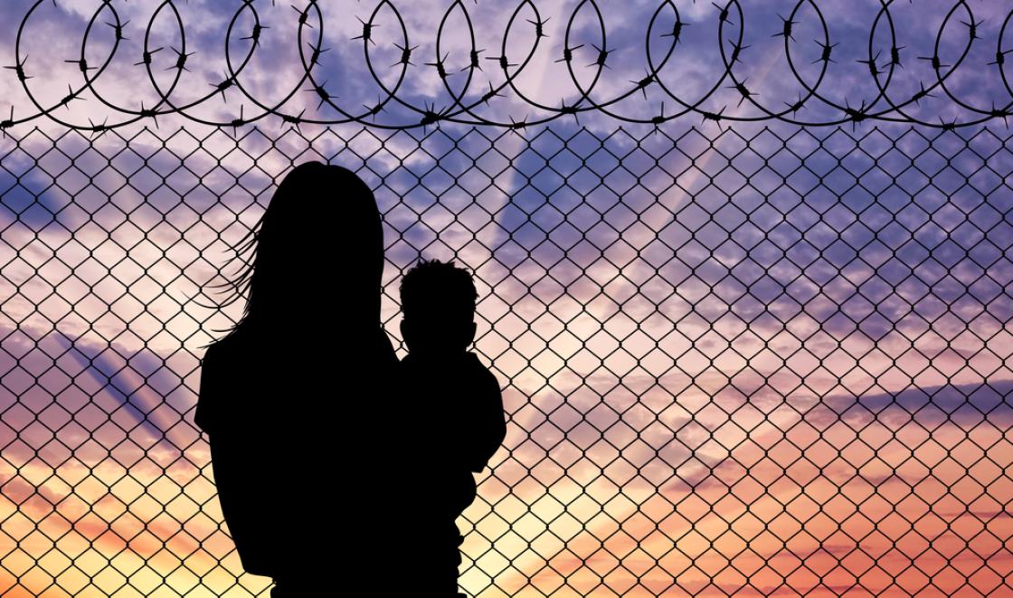 Migrant woman with child at barbed wire fence